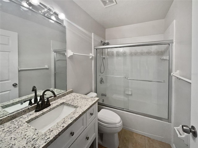 full bathroom with shower / bath combination with glass door, tile patterned floors, vanity, and toilet