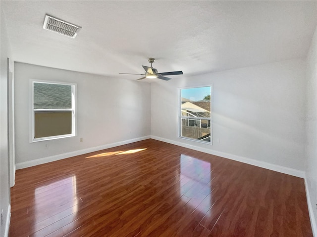 empty room featuring dark hardwood / wood-style floors, a healthy amount of sunlight, a textured ceiling, and ceiling fan