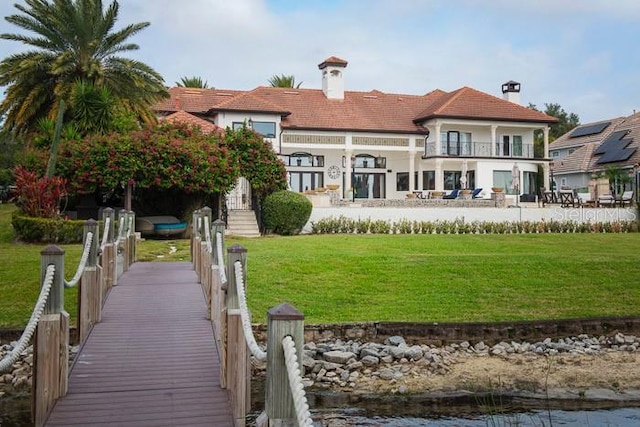 rear view of house with a balcony and a lawn