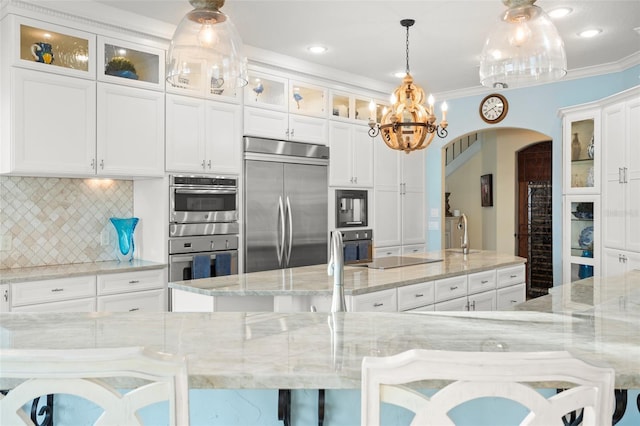 kitchen with decorative light fixtures, white cabinetry, a kitchen bar, black appliances, and light stone countertops