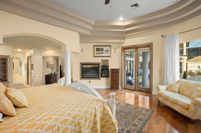 bedroom featuring hardwood / wood-style floors, connected bathroom, access to outside, and decorative columns