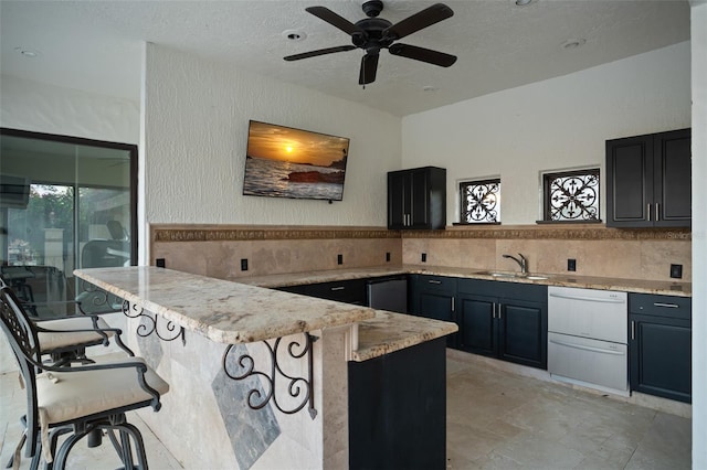 kitchen featuring sink, a textured ceiling, a breakfast bar, and kitchen peninsula