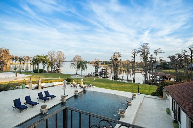 view of swimming pool featuring a water view, a patio area, and a lawn