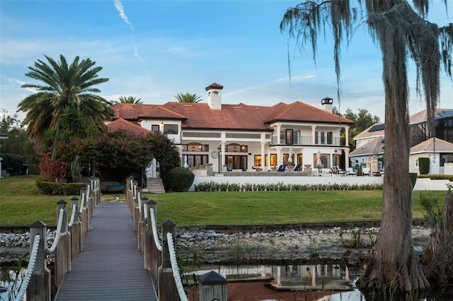 back of property with a balcony and a lawn