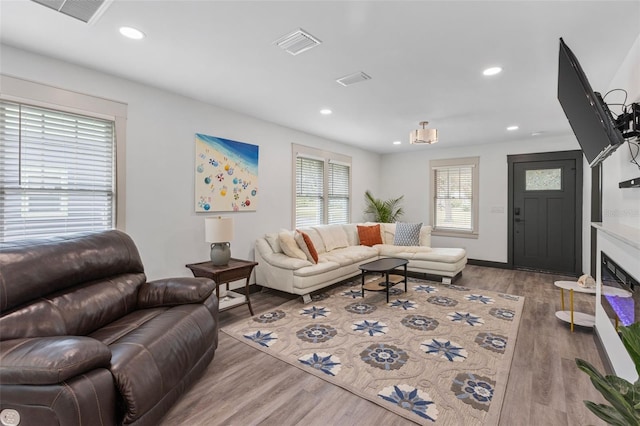 living room with recessed lighting, visible vents, wood finished floors, and a glass covered fireplace