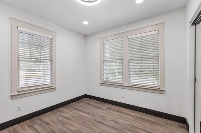 unfurnished room with recessed lighting, wood finished floors, and baseboards