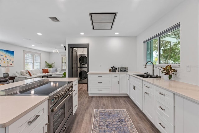 kitchen featuring stacked washer and clothes dryer, visible vents, light countertops, white cabinetry, and high end stove