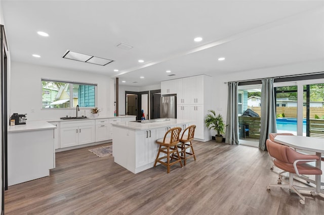 kitchen featuring a kitchen island, light countertops, a sink, and freestanding refrigerator