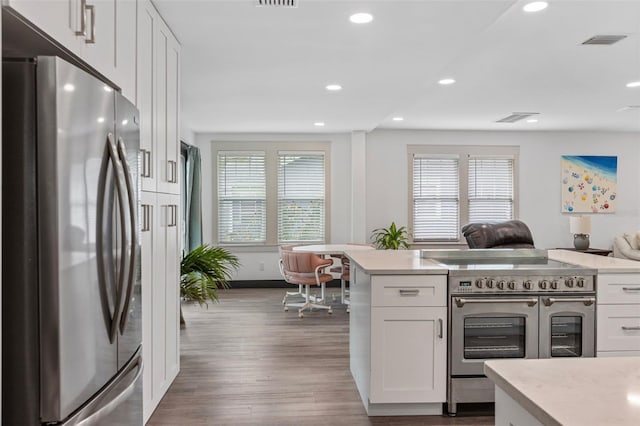 kitchen featuring stainless steel appliances, visible vents, white cabinetry, light countertops, and dark wood finished floors