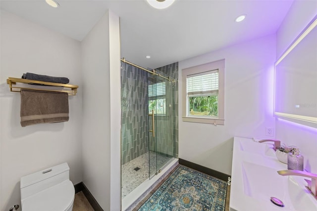 bathroom with a stall shower, a sink, toilet, and baseboards