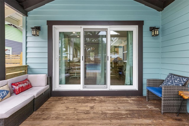 view of exterior entry with outdoor lounge area and a wooden deck