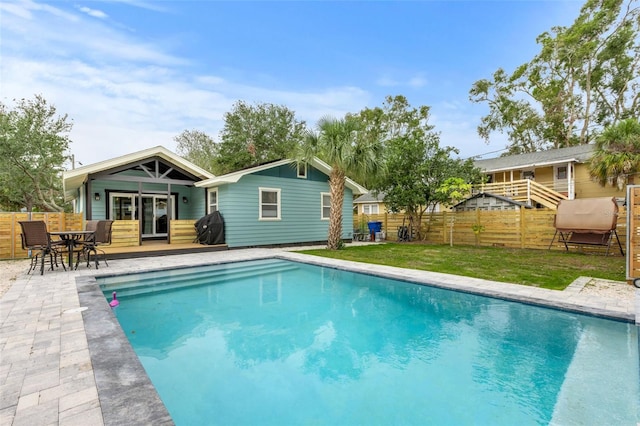 view of swimming pool featuring a lawn, a patio area, fence, and a fenced in pool