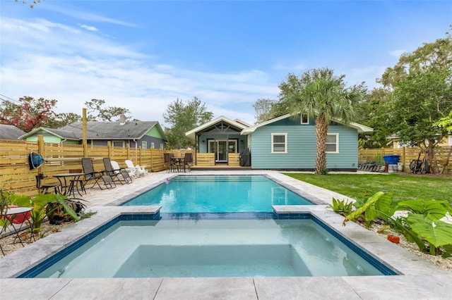 view of pool with a lawn, a fenced backyard, and a pool with connected hot tub