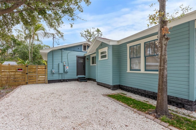 back of house with entry steps, gravel driveway, and fence