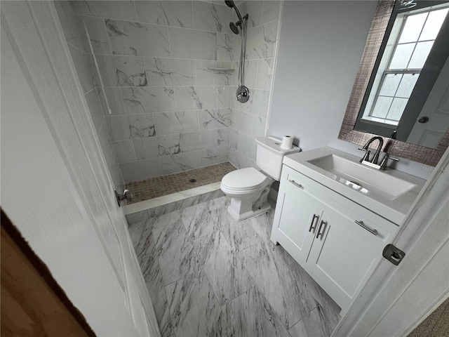 bathroom featuring toilet, vanity, and tiled shower