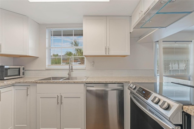 kitchen with white cabinets, ventilation hood, sink, stainless steel appliances, and light stone counters