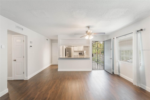 unfurnished living room with ceiling fan, dark hardwood / wood-style floors, and a textured ceiling