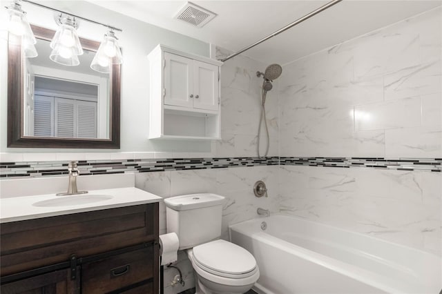 full bathroom featuring tiled shower / bath combo, toilet, vanity, and tile walls