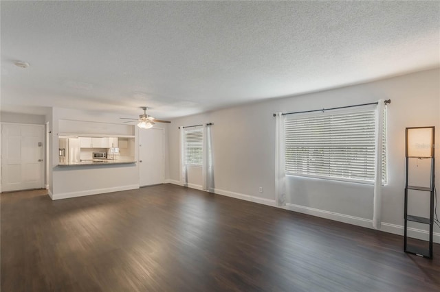 unfurnished living room featuring ceiling fan, dark hardwood / wood-style floors, and a textured ceiling