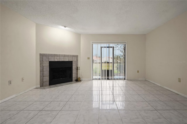 unfurnished living room featuring a tiled fireplace, light tile patterned flooring, and a textured ceiling