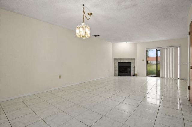 unfurnished living room featuring a tile fireplace, light tile patterned flooring, a textured ceiling, and an inviting chandelier