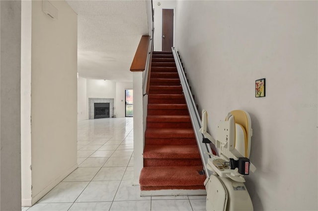 staircase with tile patterned flooring, a textured ceiling, and a tile fireplace