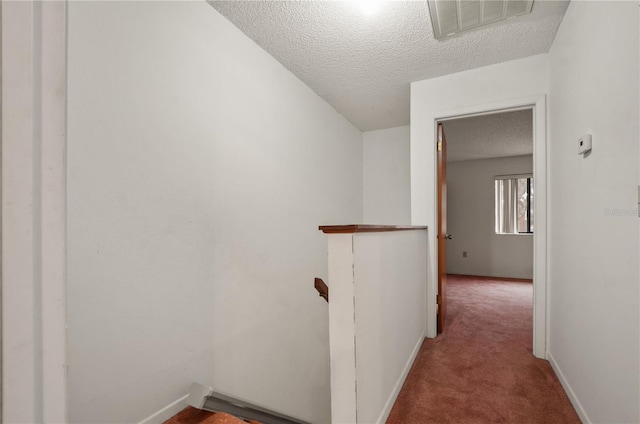 hall featuring carpet flooring and a textured ceiling