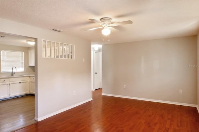 unfurnished room with a textured ceiling, dark hardwood / wood-style floors, ceiling fan, and sink