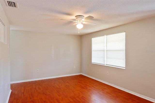 empty room with ceiling fan, a textured ceiling, and hardwood / wood-style flooring