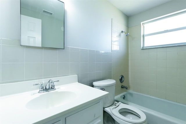 full bathroom featuring toilet, vanity, tile walls, and tiled shower / bath