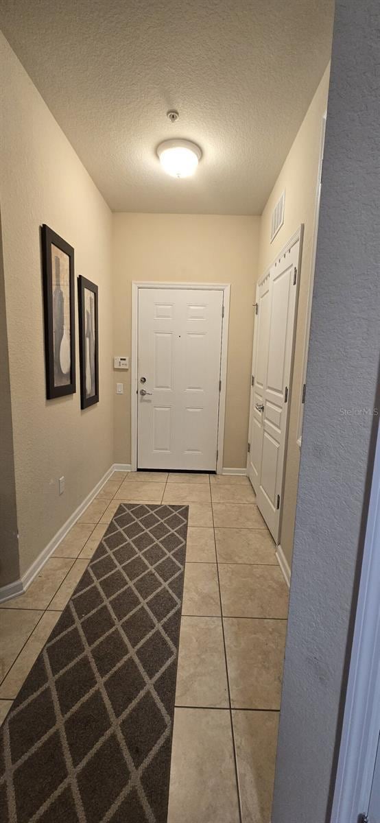 doorway featuring light tile patterned floors and a textured ceiling