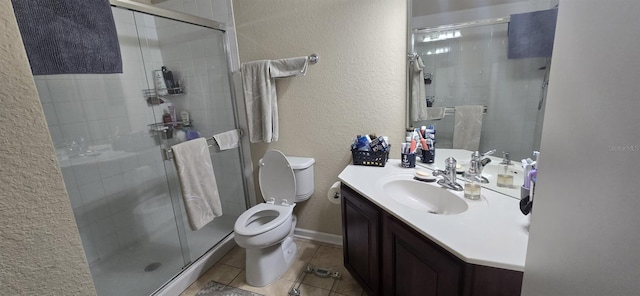 bathroom featuring tile patterned floors, vanity, toilet, and a shower with shower door