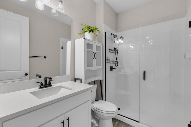 bathroom featuring vanity, hardwood / wood-style flooring, toilet, and a shower with shower door