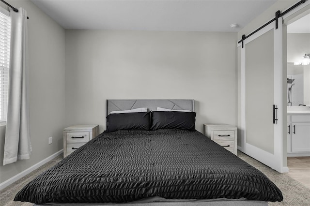 carpeted bedroom featuring a barn door and ensuite bathroom