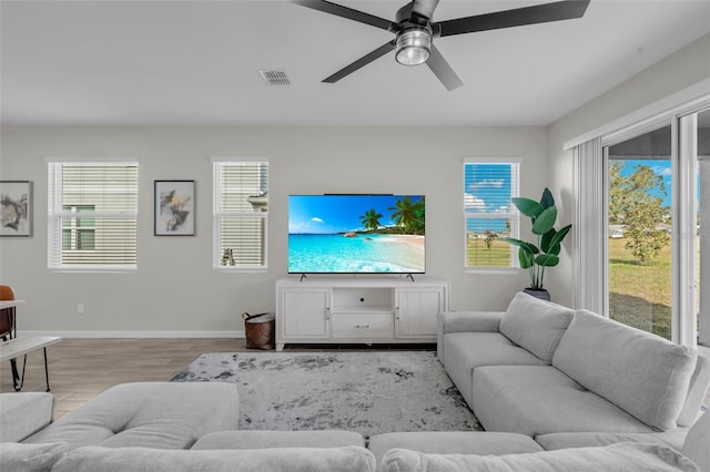 living area with ceiling fan, wood finished floors, visible vents, and baseboards