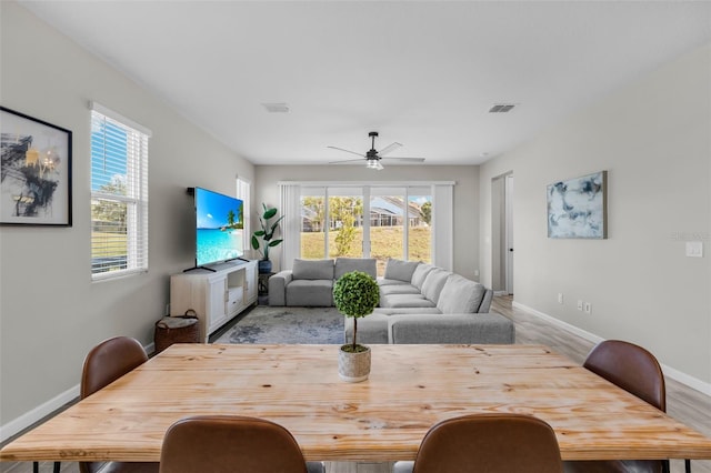 dining area featuring a ceiling fan, wood finished floors, visible vents, and baseboards