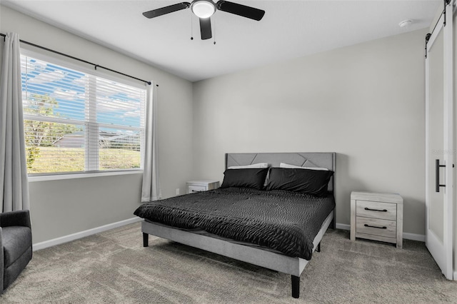 bedroom featuring a ceiling fan, carpet, baseboards, and a barn door