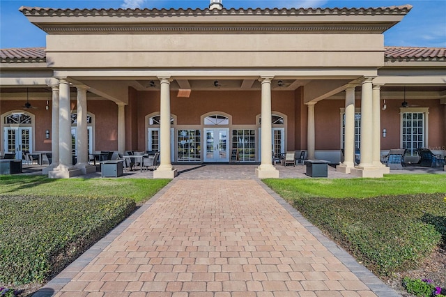 back of property featuring a tiled roof, french doors, a yard, and stucco siding