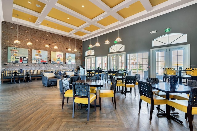dining area featuring a high ceiling, beam ceiling, coffered ceiling, and plenty of natural light