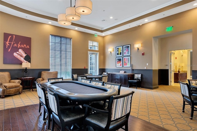 recreation room featuring carpet floors, a wainscoted wall, a raised ceiling, a high ceiling, and recessed lighting