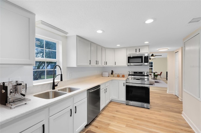 kitchen featuring light countertops, appliances with stainless steel finishes, a sink, and white cabinets