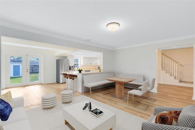 living room with baseboards, visible vents, light wood-style flooring, and crown molding