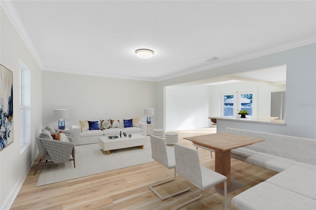 living area featuring visible vents, crown molding, baseboards, and wood finished floors