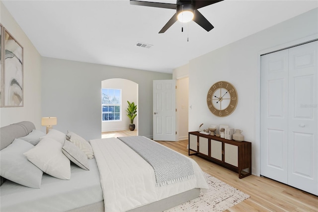 bedroom with a ceiling fan, arched walkways, visible vents, and light wood-style flooring