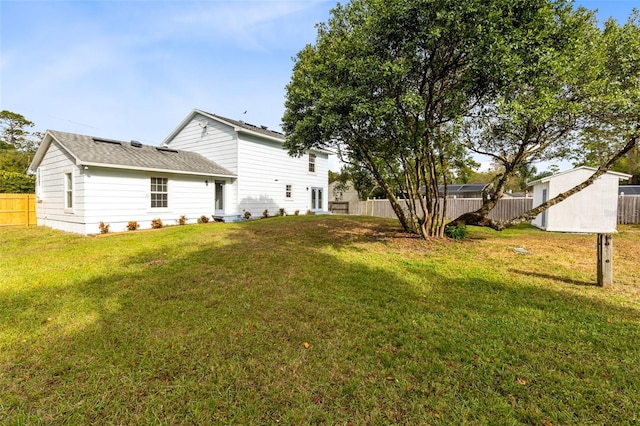 rear view of house with a storage unit and a yard