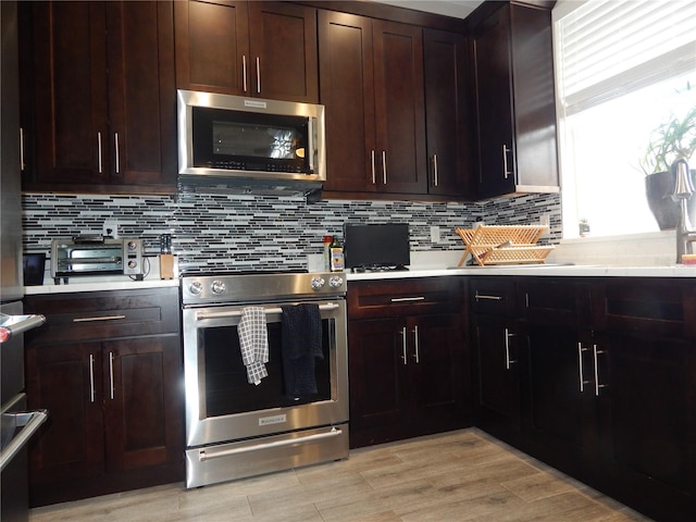 kitchen with tasteful backsplash, dark brown cabinetry, stainless steel appliances, and light wood-type flooring