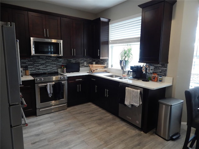 kitchen featuring sink, dark brown cabinetry, stainless steel appliances, and tasteful backsplash