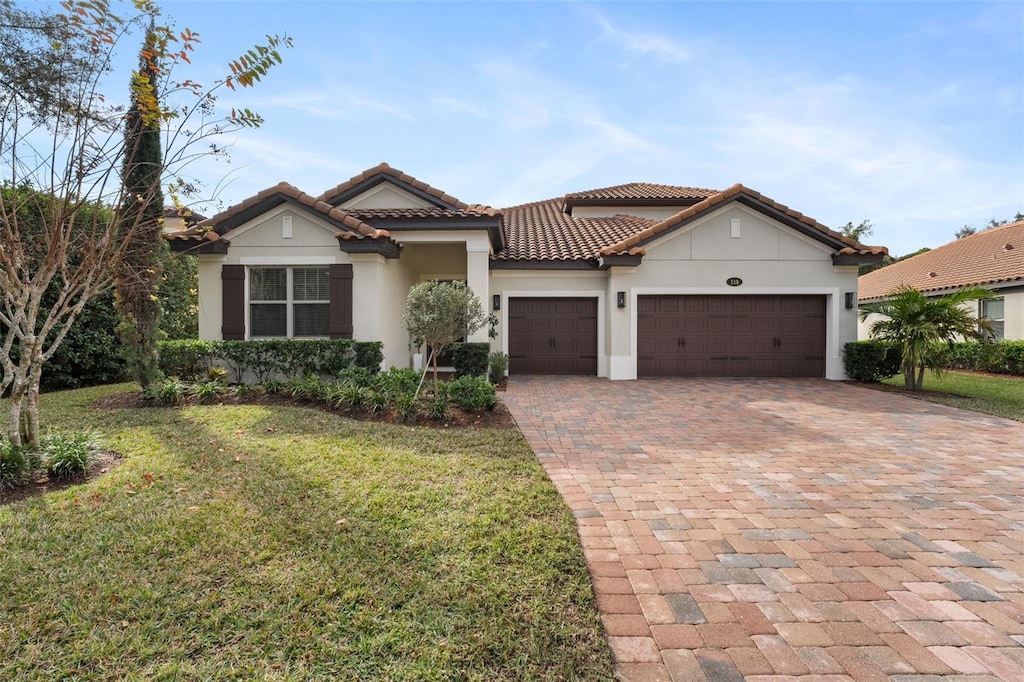 mediterranean / spanish home featuring a garage and a front yard