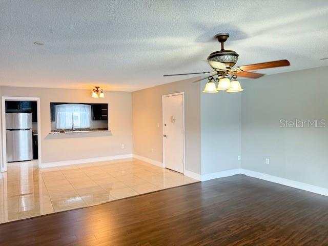 unfurnished living room featuring ceiling fan, light hardwood / wood-style floors, and a textured ceiling