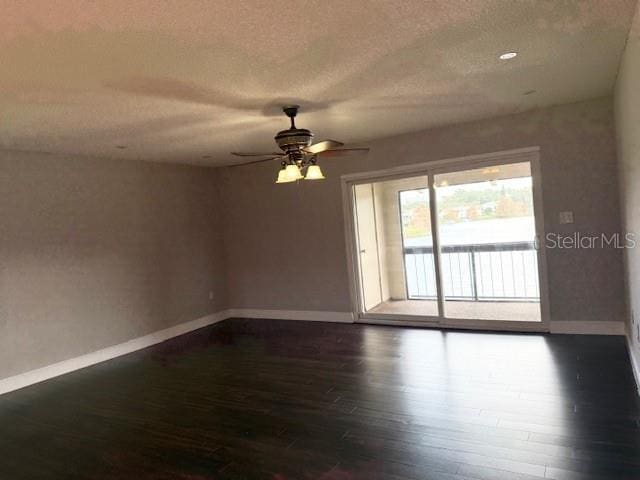 empty room with ceiling fan, dark hardwood / wood-style flooring, and a textured ceiling